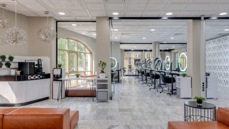 A bright, spacious modern beauty studio with white columns, styling stations and leather sofas