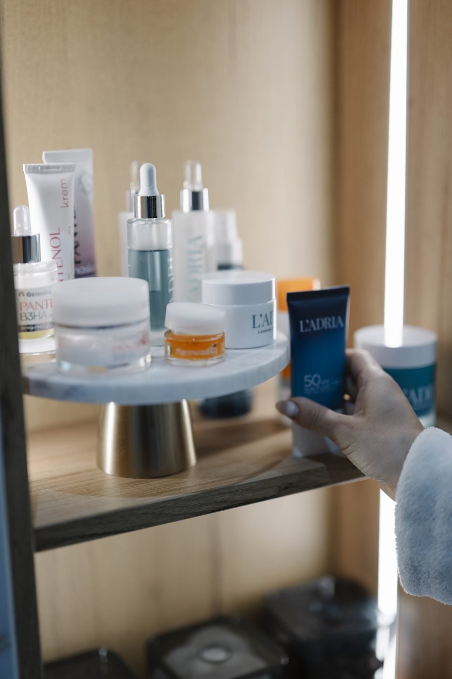A shopper reaches for a skincare product on a softly lit display shelf