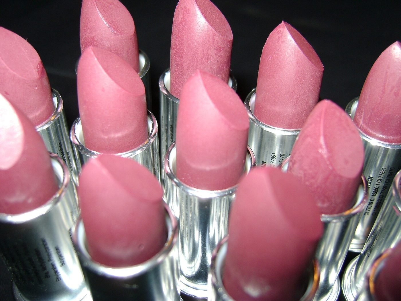Close-up of several pink lipsticks in silver tubes